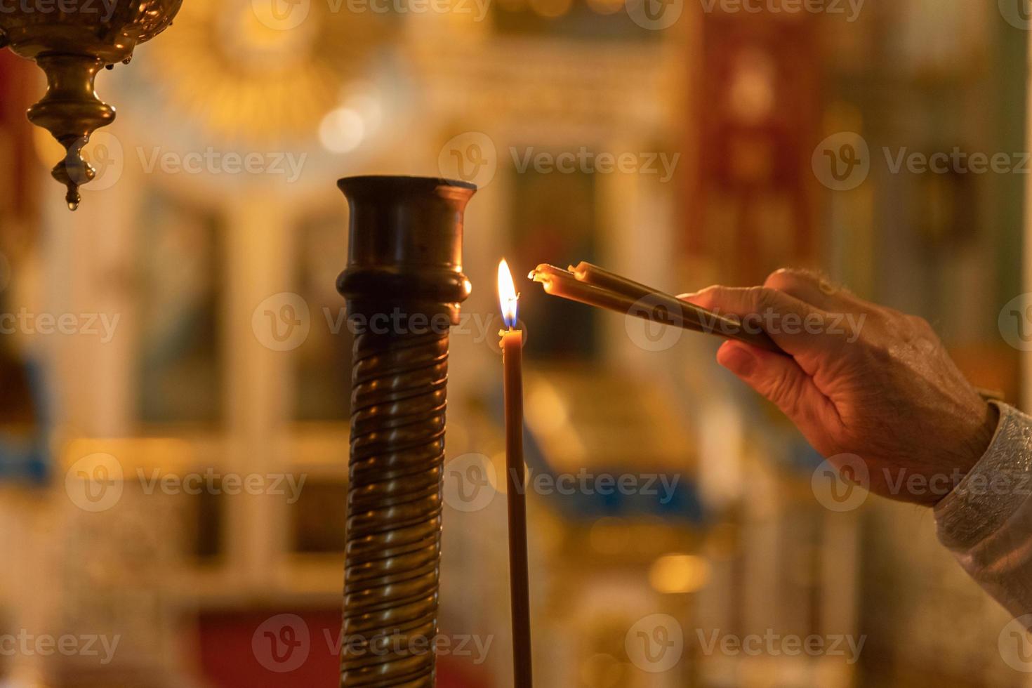 Chiesa ortodossa. cristianesimo. mano del sacerdote che accende candele accese nella tradizionale chiesa ortodossa alla vigilia di Pasqua o a Natale. religione fede pregare simbolo. foto