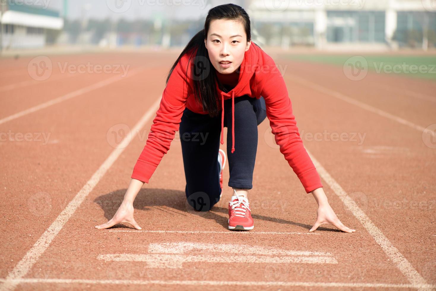 donna asiatica atletica in posizione iniziale in pista foto