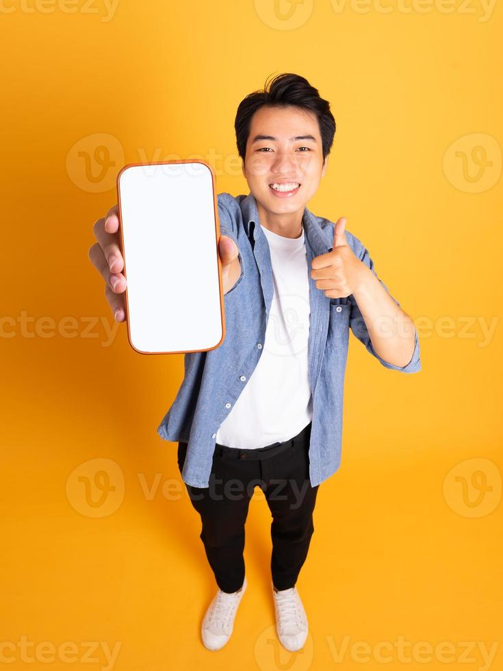 Immagine di asiatico uomo Tenere Telefono, isolato su giallo sfondo foto