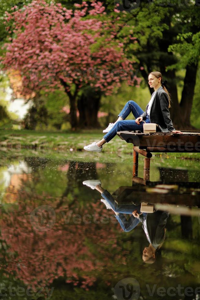 ritratto di bellissimo donna vicino un' di legno ponte di il lago a soleggiato giorno. bellissimo ragazza su un' di legno ponte su un' lago foto