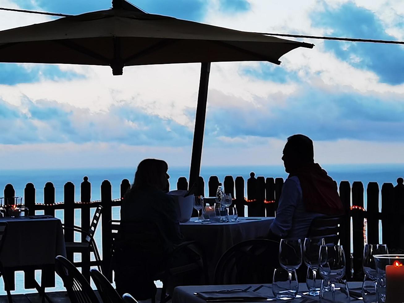 un' coppia è mangiare a il tavolo di un' ristorante con un' mare Visualizza nel il ligure ovest di finale ligure foto