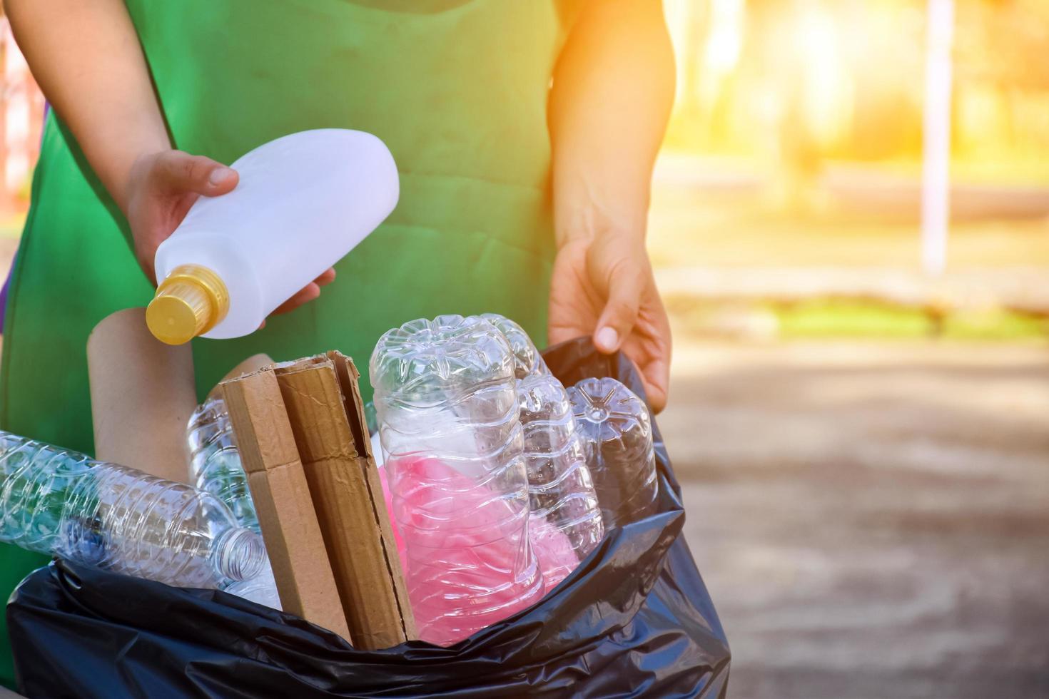 proprietario di casa è separare bottiglie, carta, uovo cartoni e altro cose nel il nero plastica Borsa nel davanti di il Casa, concetto per riducendo globale riscaldamento, Salvataggio nostro mondo, morbido e selettivo messa a fuoco. foto