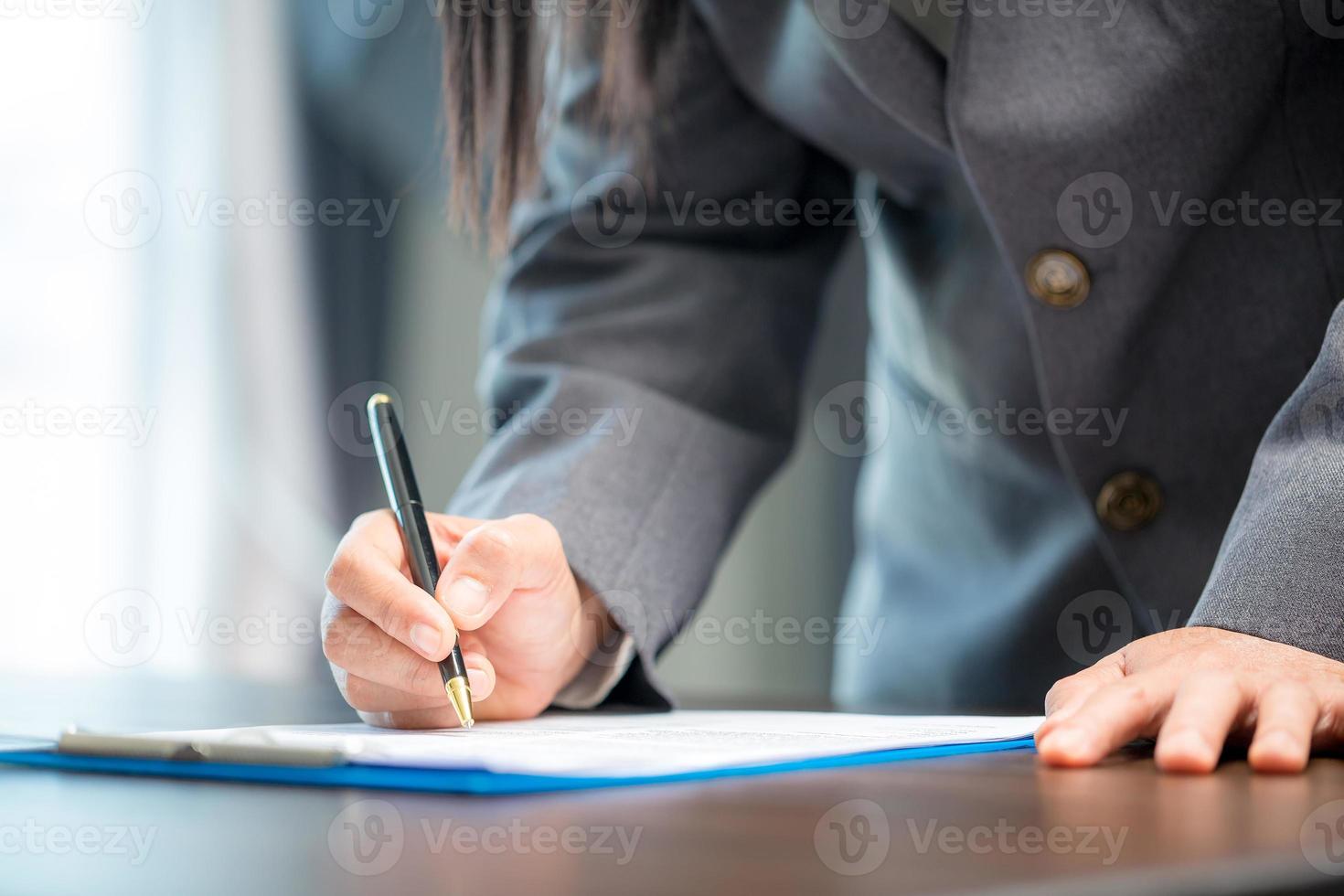 posto di lavoro avvicinamento persona professionale donna d'affari seduta a scrivania hold penna firma o firma contrarre carta. dipendente donna scrittura accordo documento su lavoro d'ufficio modulo aziendale a opera ufficio foto