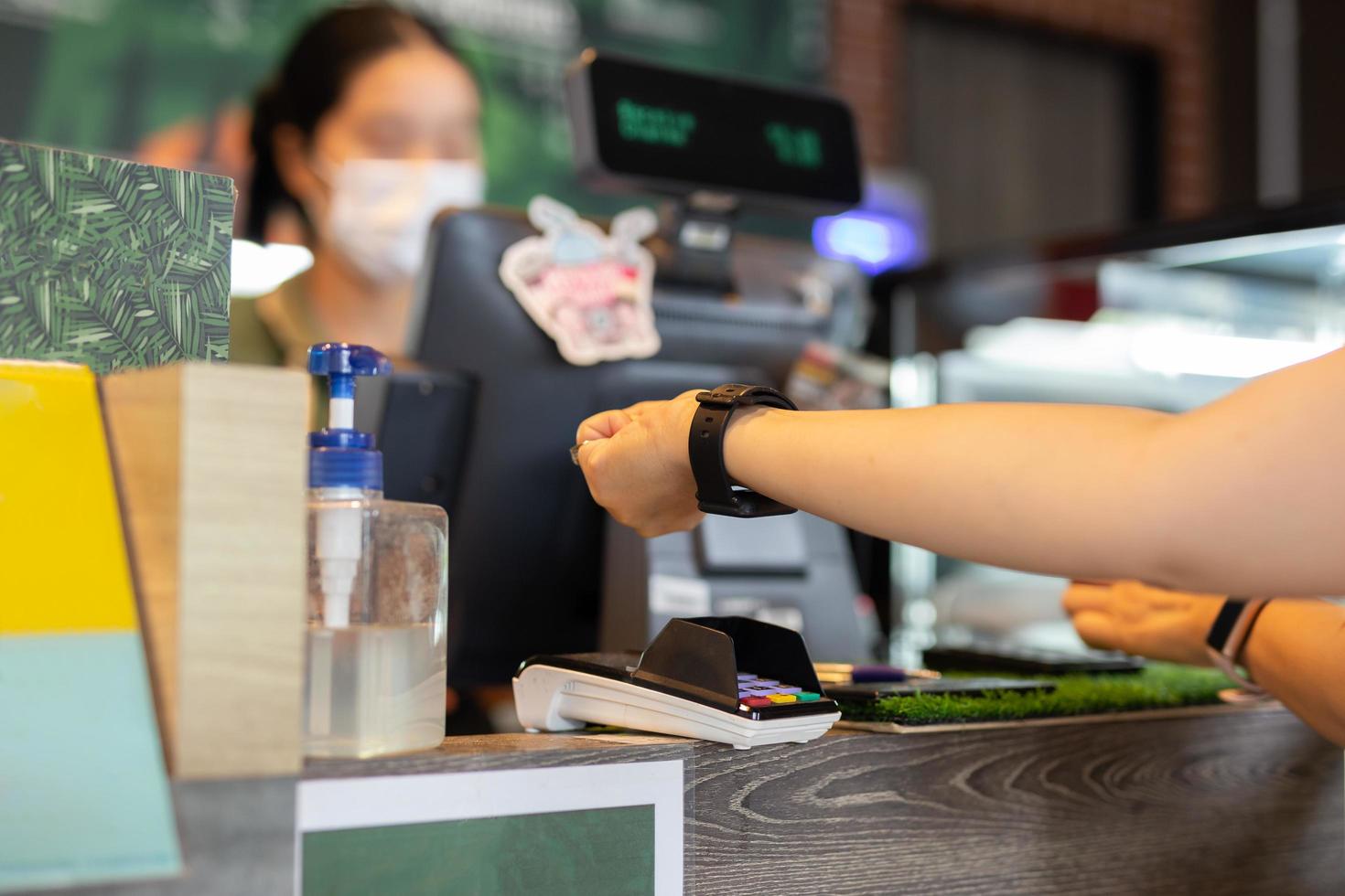 donna pagare conto attraverso orologio intelligente utilizzando nfc tecnologia nel bar. foto
