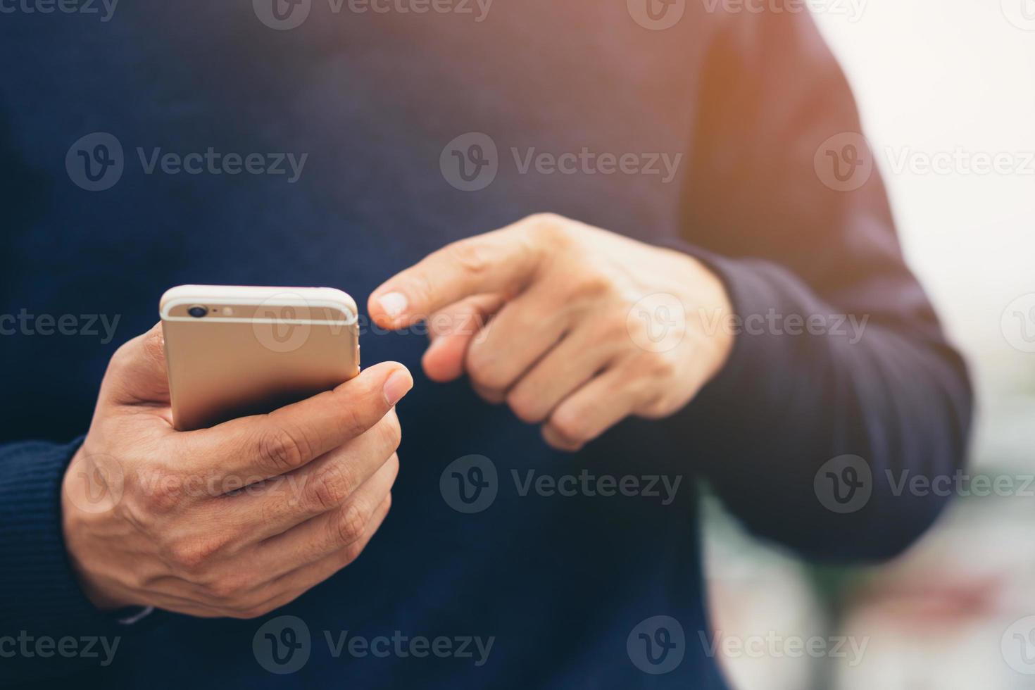 il giovane indossa una camicia a quadri. mano ravvicinata utilizzando il telefono cellulare durante il riposo sul divano. seduto a guardare il messaggio sullo smartphone mobile durante la pausa relax. focalizzazione morbida. foto