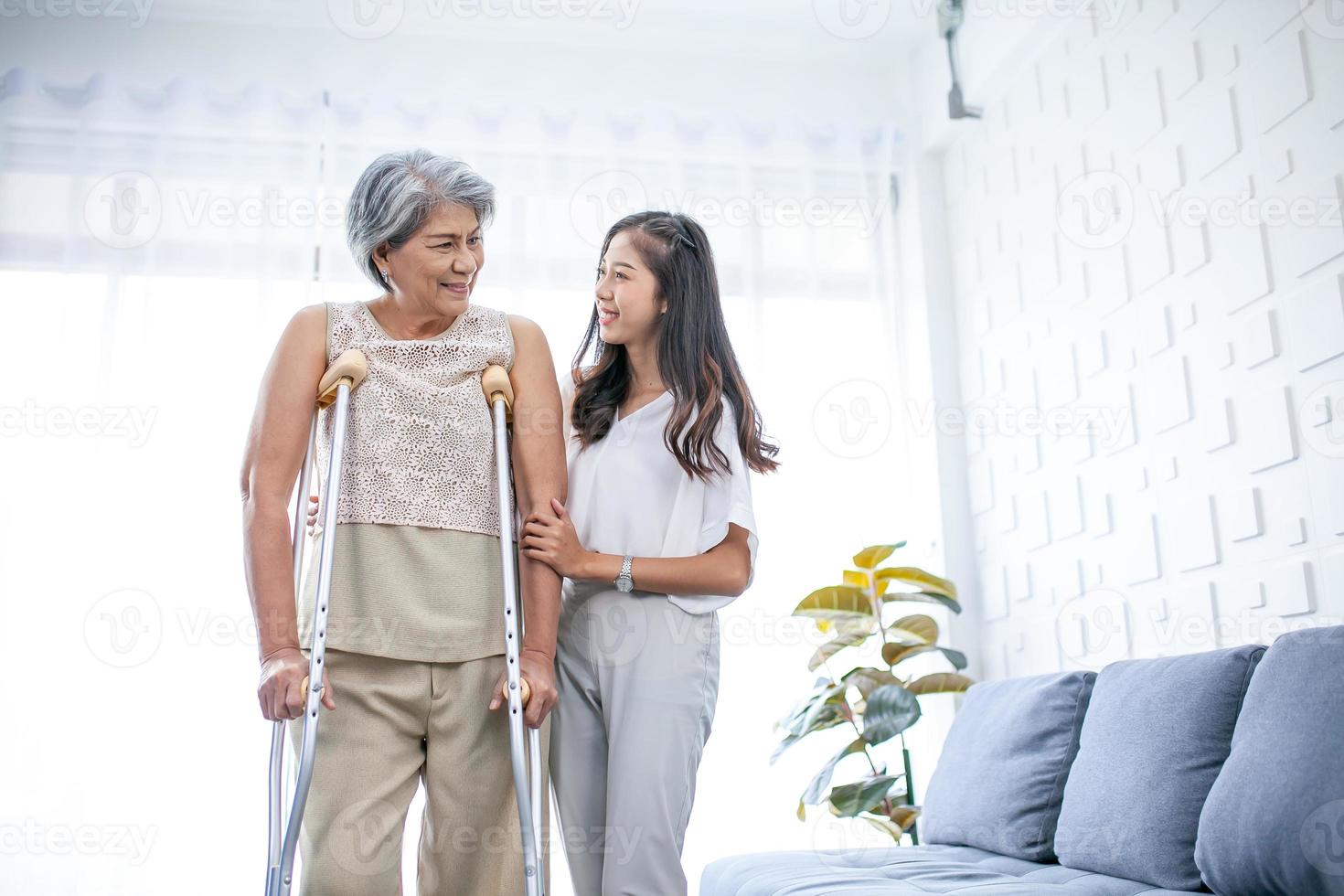 Aiuto e cura per un' anziano asiatico nonna o vecchio donna utilizzando un' salutare camminatore mentre a piedi a casa. foto