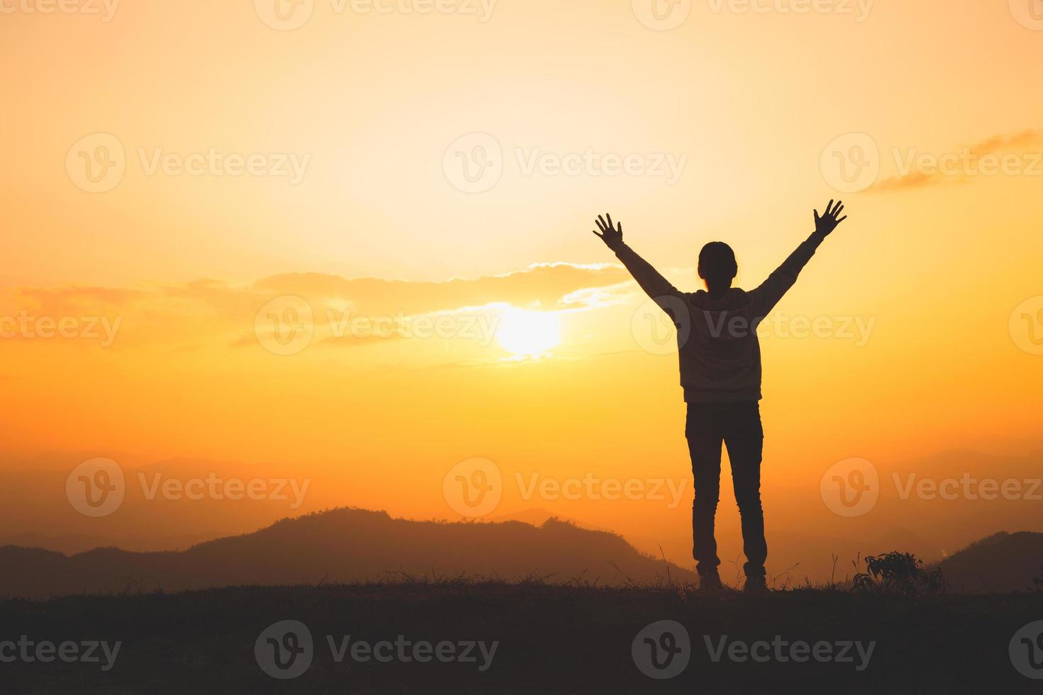 l'uomo alza la mano in cima alla montagna e al tramonto, la libertà e il concetto di avventura di viaggio. credenze religiose, copia spazio. foto