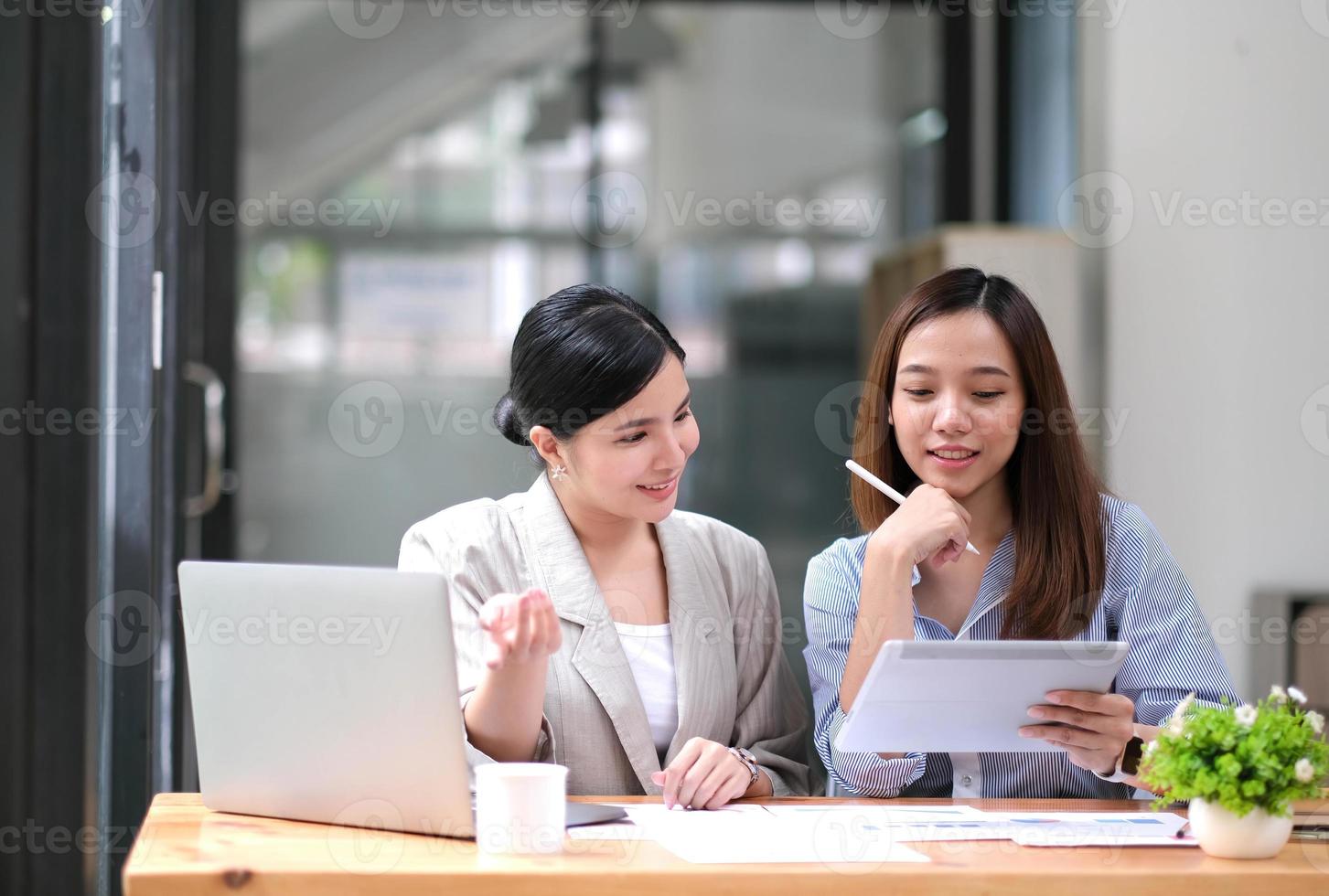 due giovani donne d'affari asiatiche discutono con la presentazione di una nuova idea di progetto di avvio, analizzano le statistiche finanziarie e di pianificazione e il mercato degli investimenti in ufficio. foto