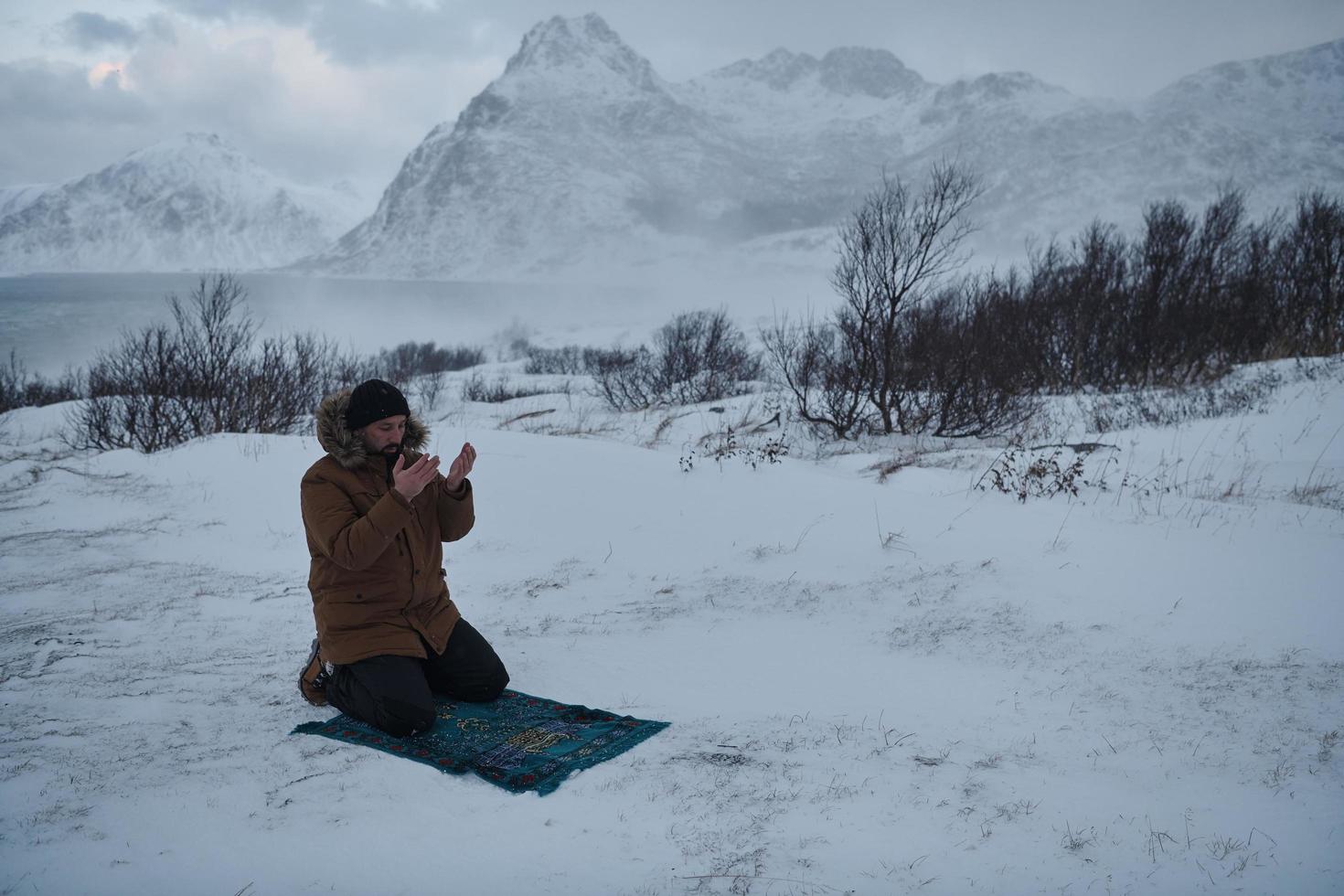 viaggiatore musulmano che prega in una fredda giornata invernale nevosa foto