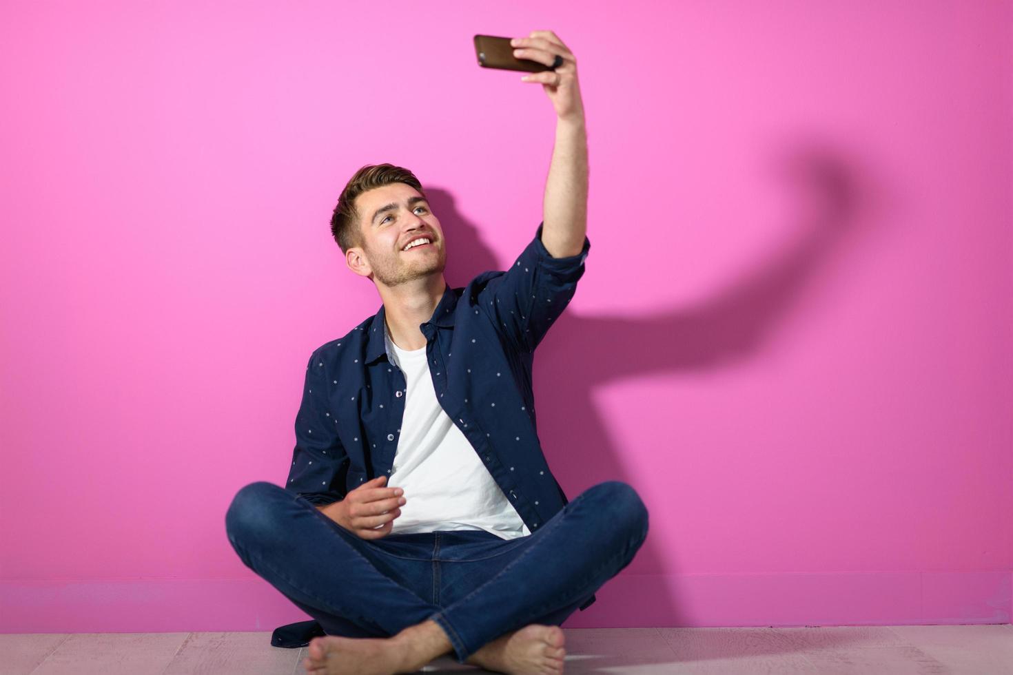 uomo seduta su il pavimento di il Casa e utilizzando il Telefono foto