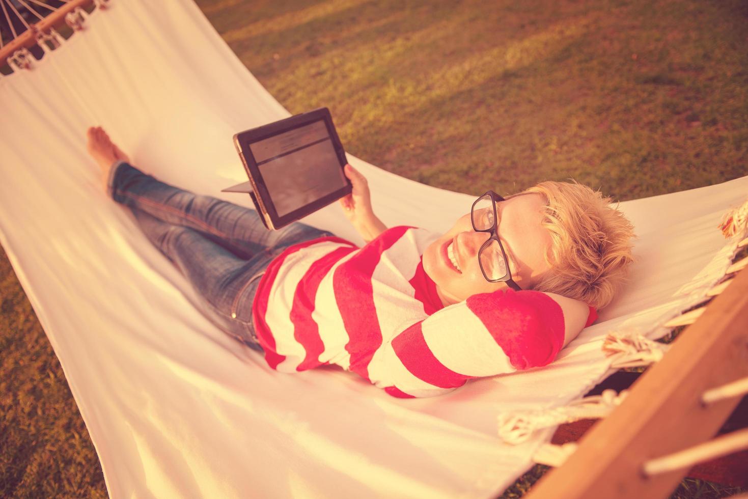 donna utilizzando un' tavoletta computer mentre rilassante su amaca foto