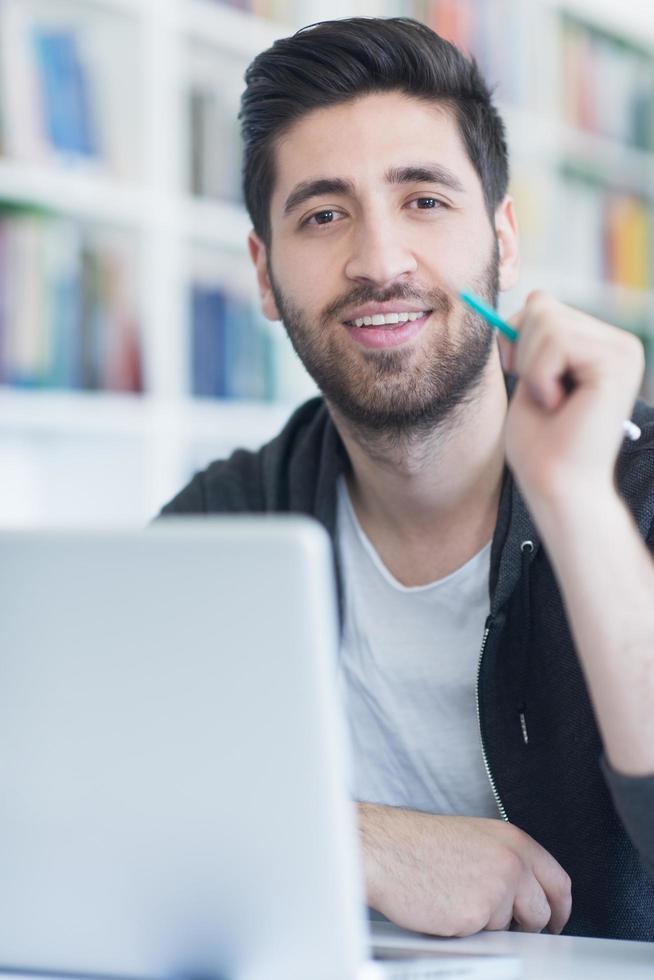 alunno nel scuola biblioteca utilizzando il computer portatile per ricerca foto