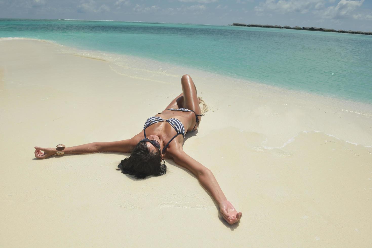 bellissimo giovane donna su spiaggia avere divertimento e rilassare foto