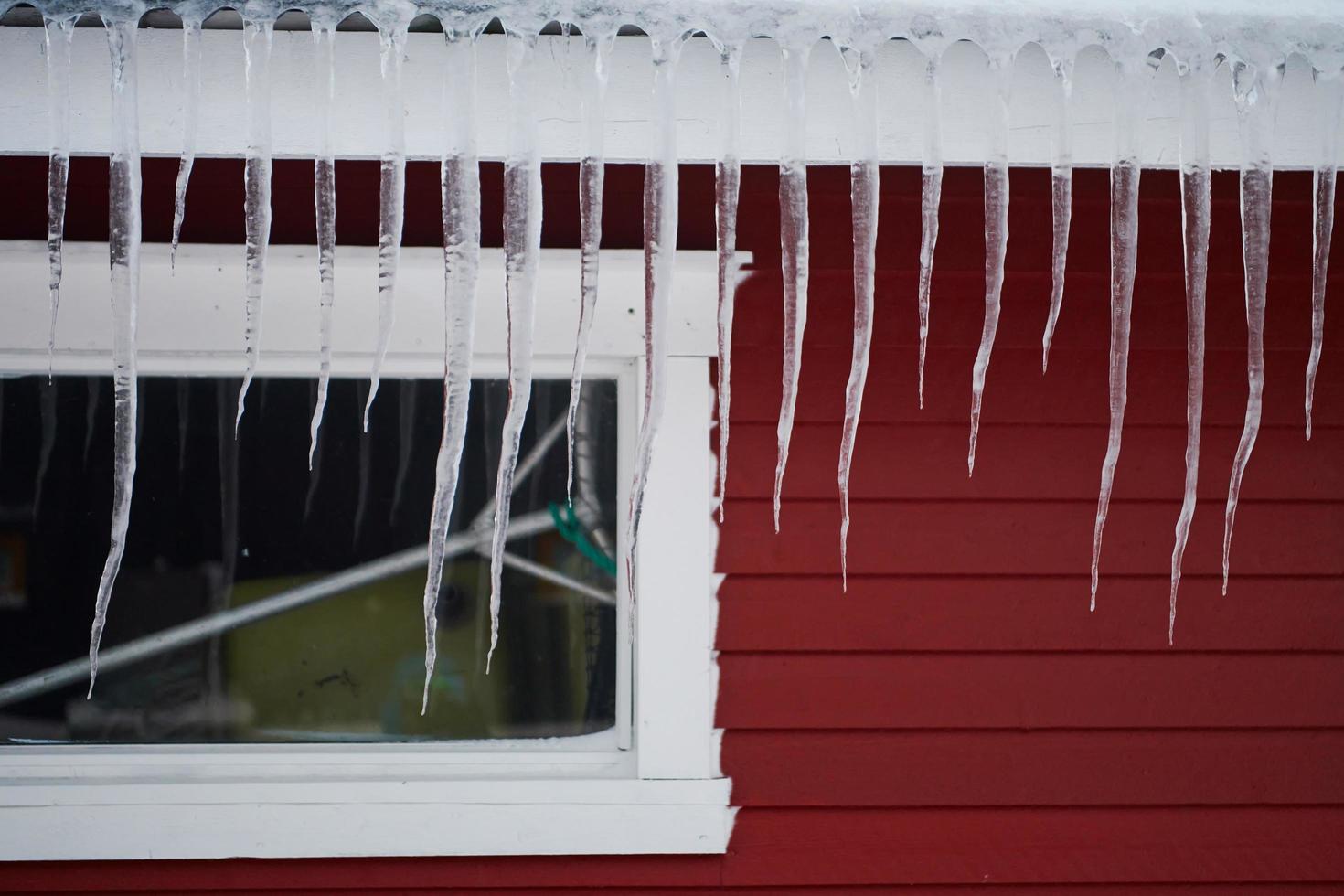 ghiaccioli sul tetto di una casa rossa in Norvegia foto