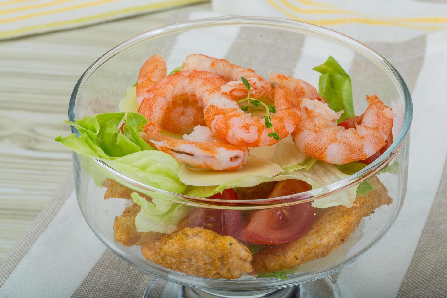 Cesare insalata con gamberetti nel un' ciotola su di legno sfondo foto