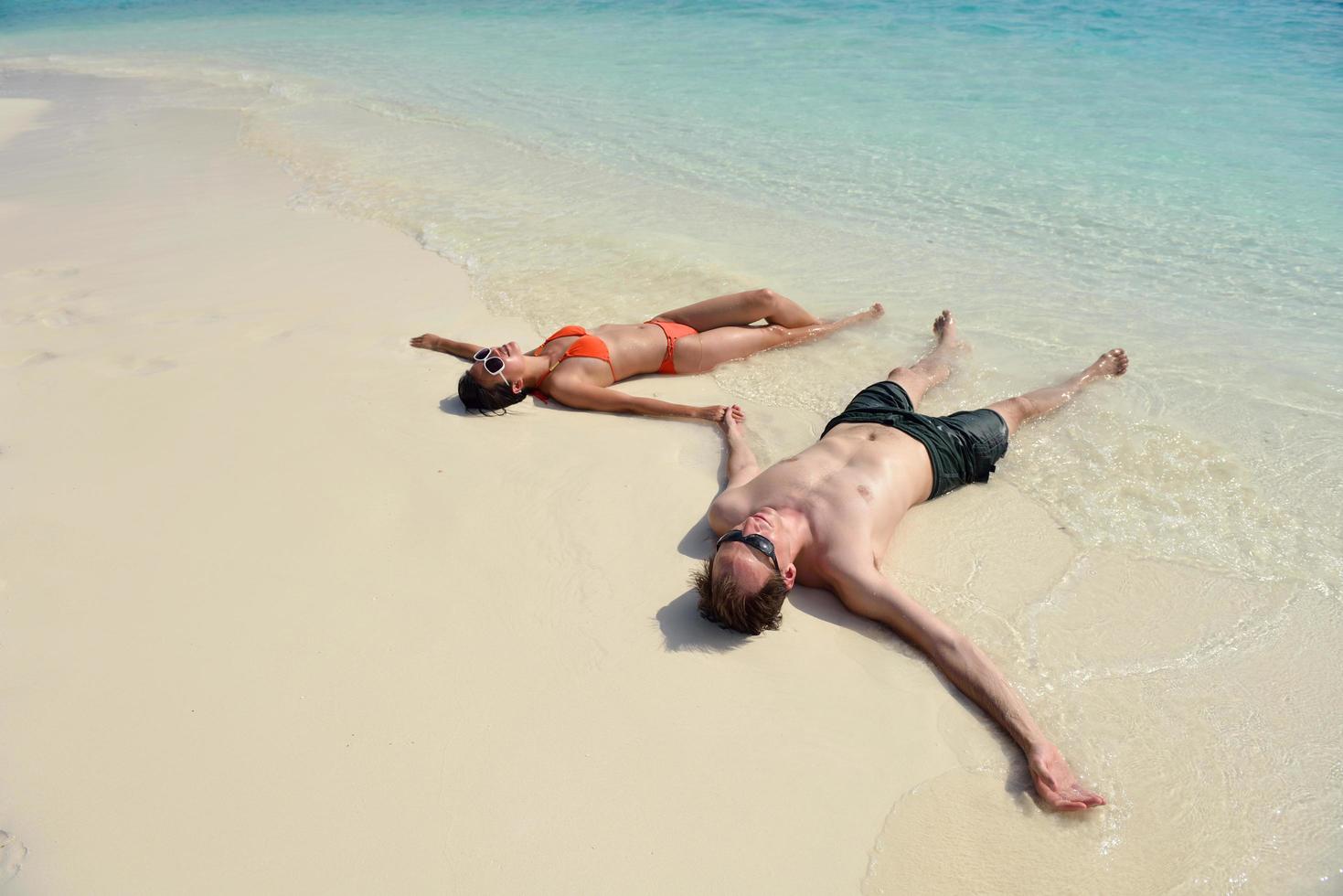 la giovane coppia felice si diverte sulla spiaggia foto