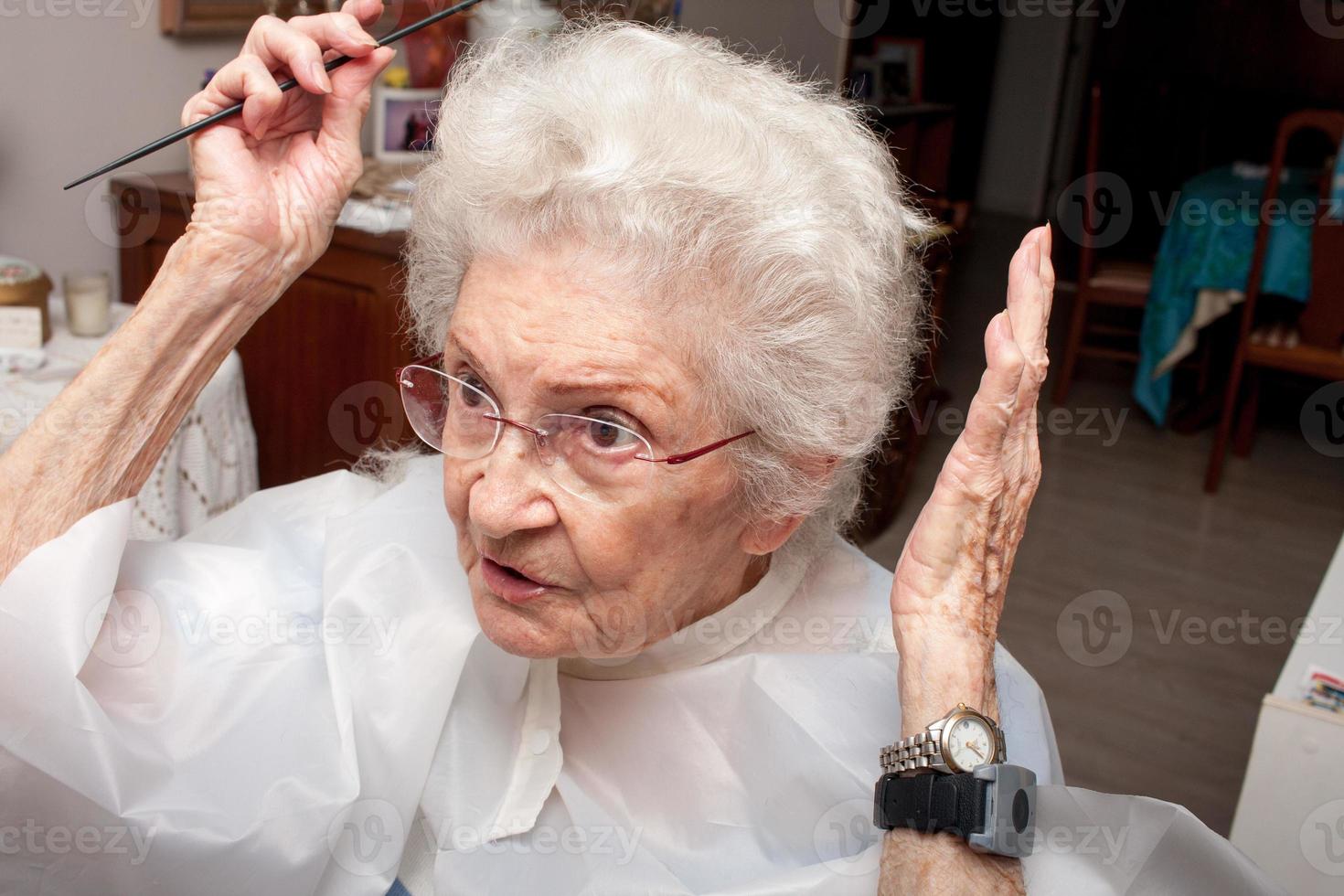 signora anziana che si taglia i capelli nel comfort della sua casa foto