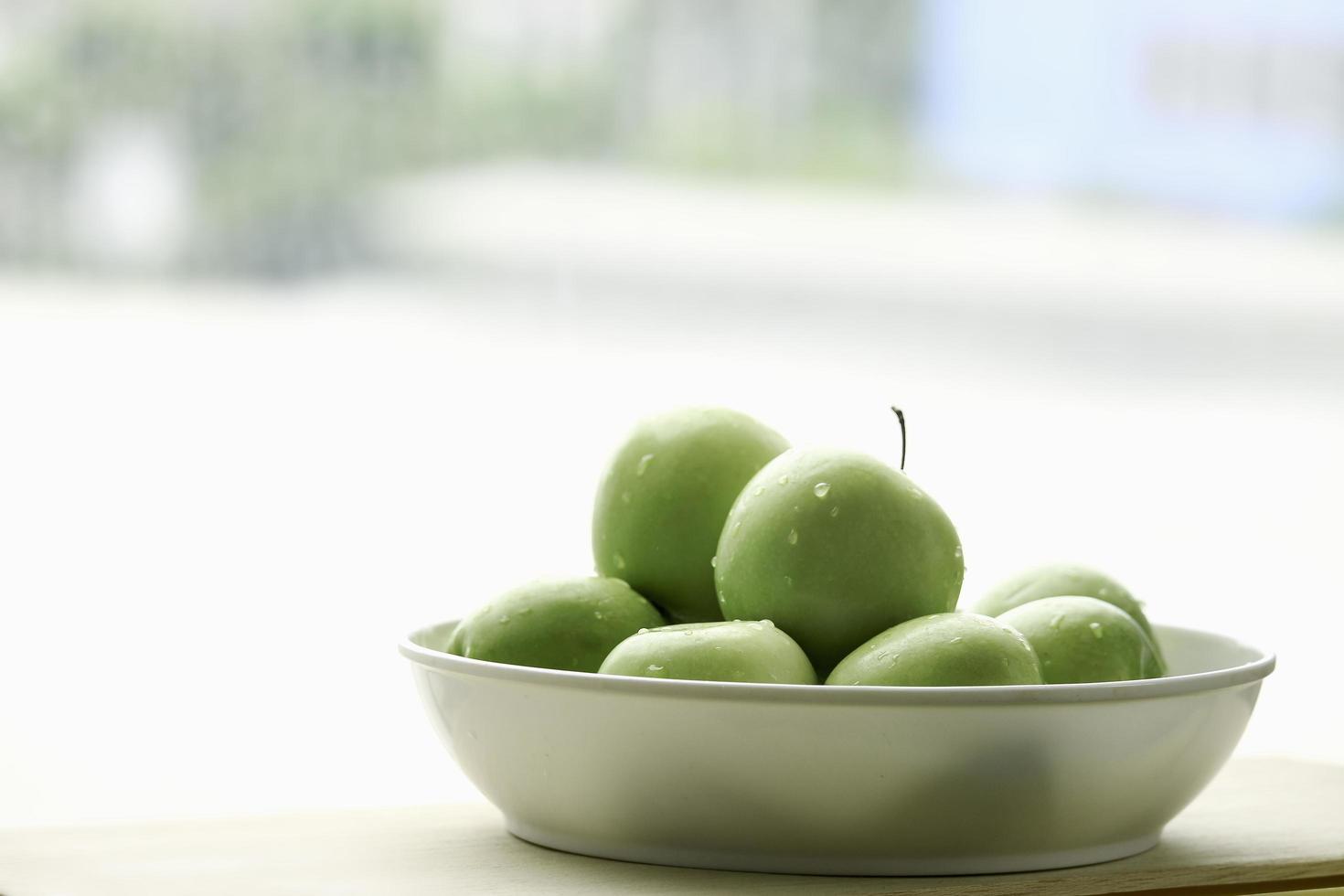 frutta cruda mela verde matura in ciotola bianca su tavola di legno, prodotti freschi biologici sani foto