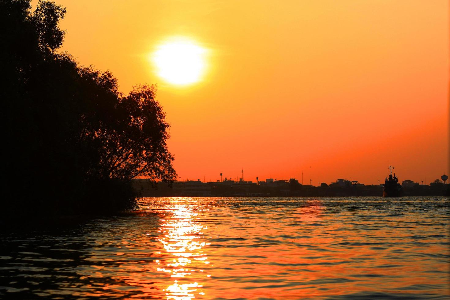 bellissimo tramonto sul fiume con nave da carico e barca in tailandia foto