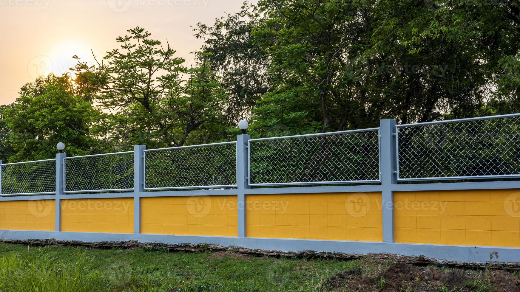 recinzione di muro di cemento giallo con grata in acciaio nel giardino forestale. foto