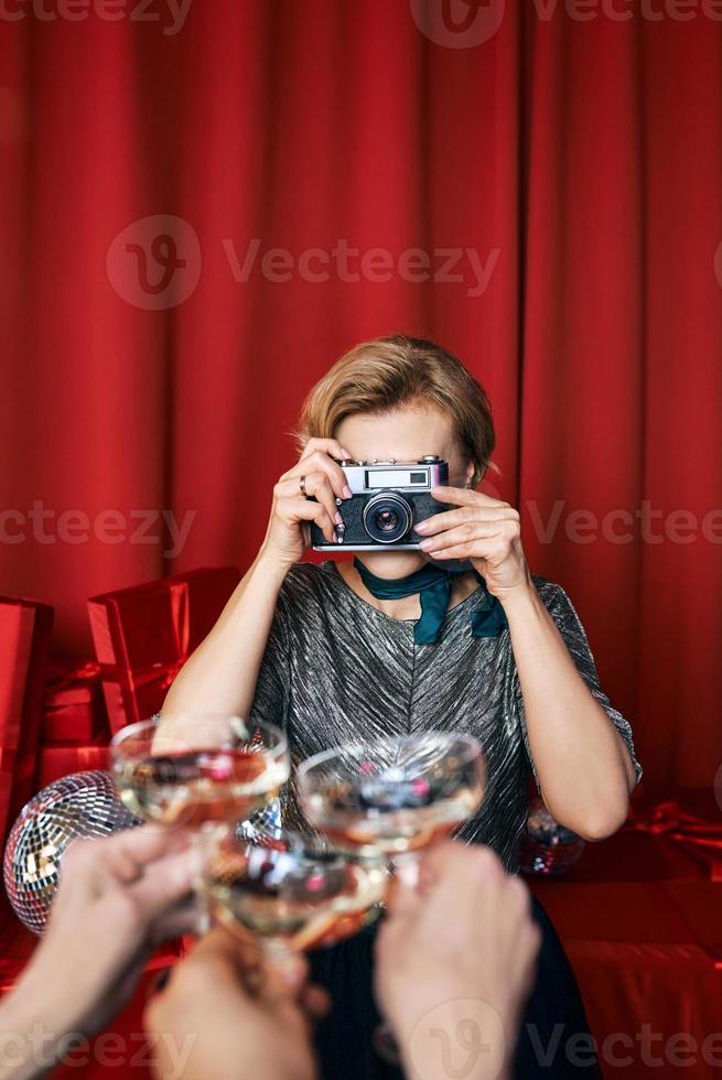 bella donna allegra del fotografo alla celebrazione della festa su sfondo di tende rosse. professione, concetto di festa foto