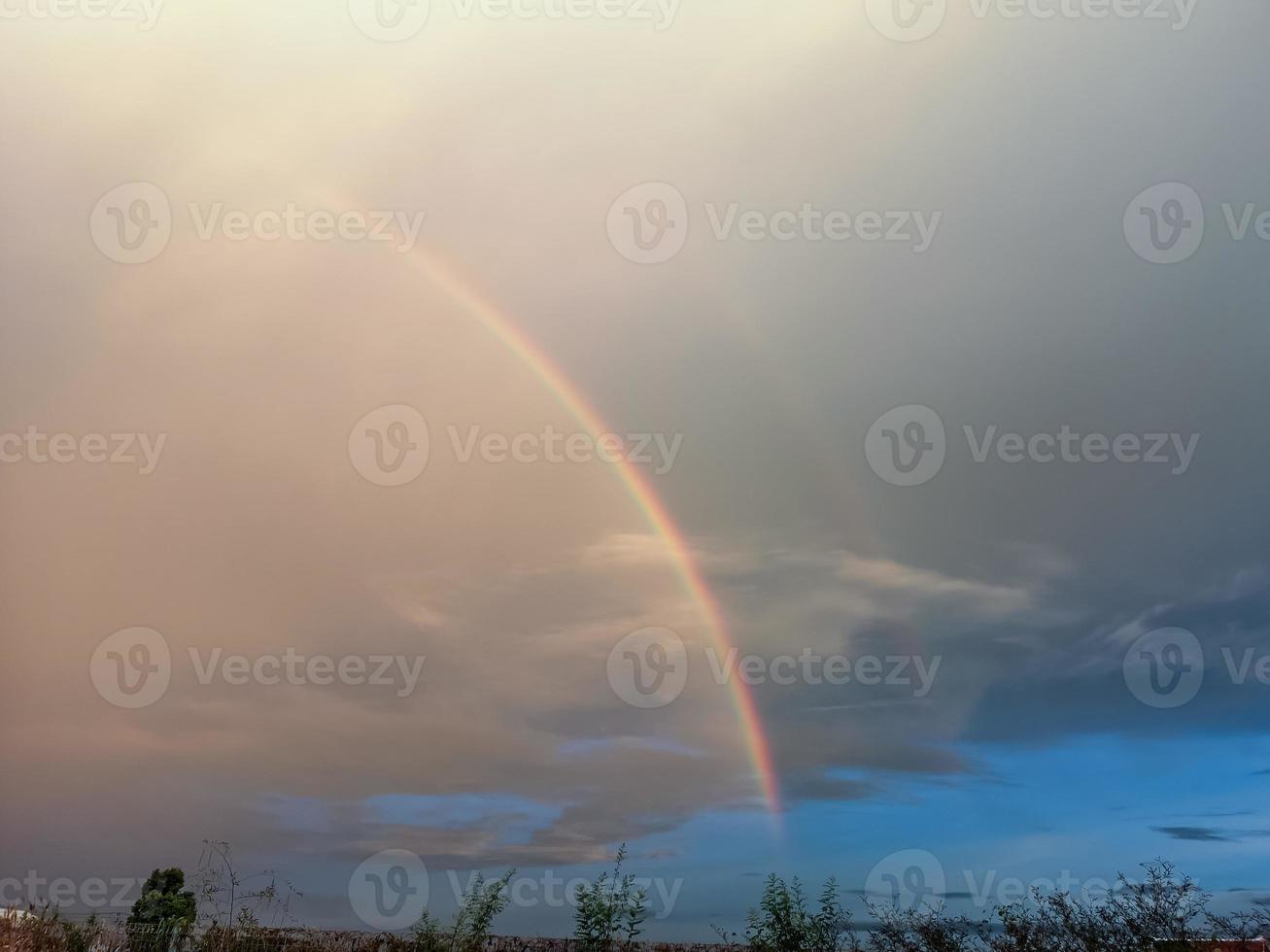 arcobaleno al di sopra di il campo dopo pioggia foto