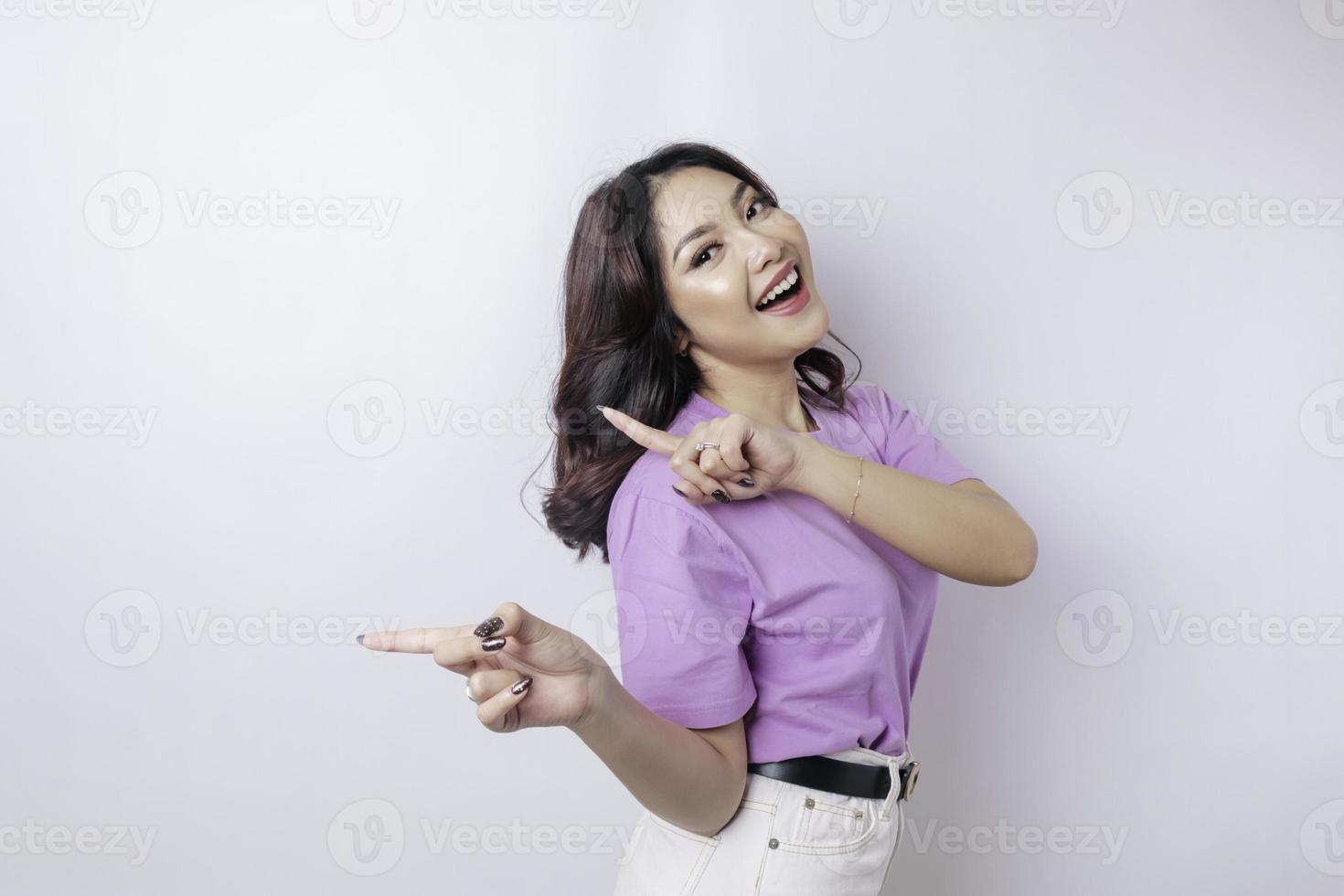 sorridente bellissimo asiatico donna puntamento dito per vuoto spazio accanto sua isolato bianca sfondo foto