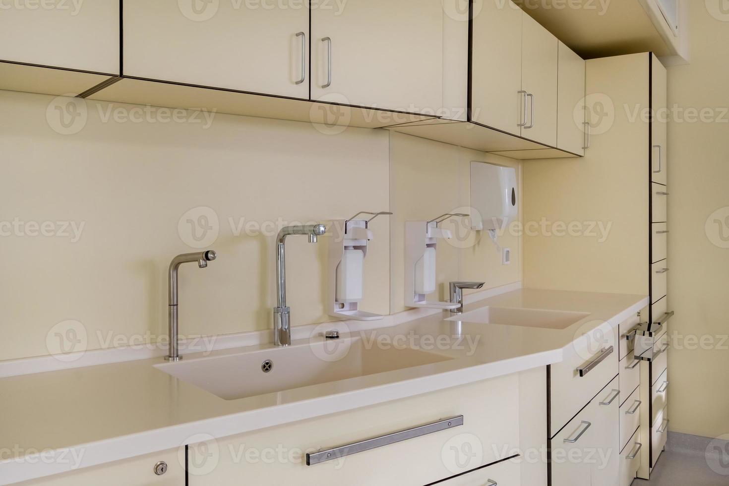 gomito dispenser sapone e antisettico o disinfettante a parete per la disinfezione delle mani e rubinetto dell'acqua lavabo con rubinetto bagno o clinica foto