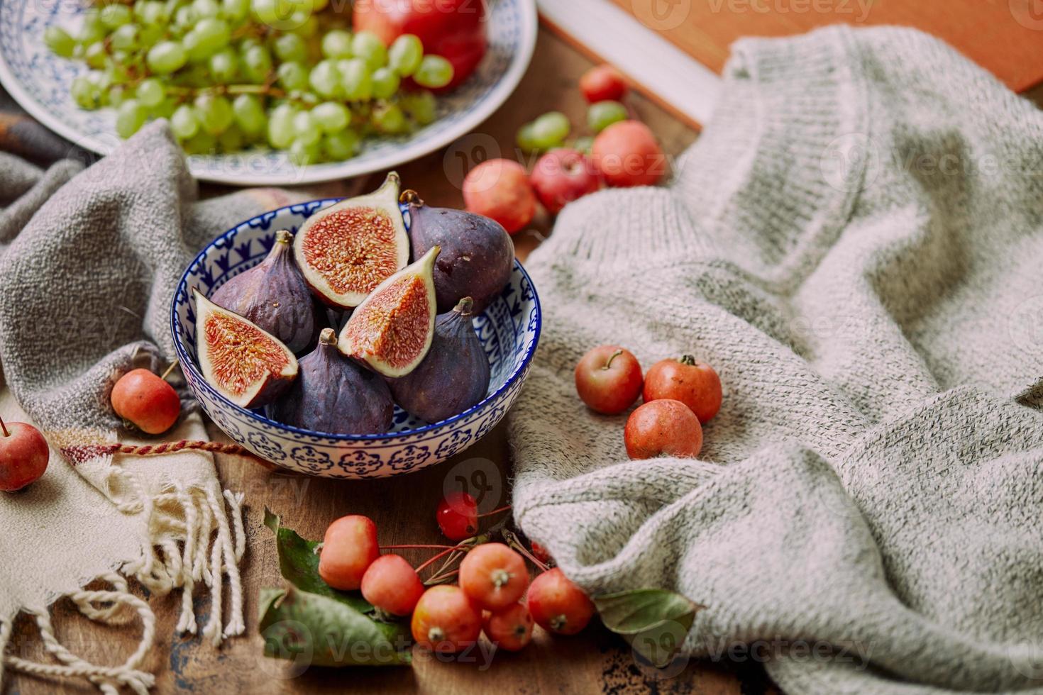 piatto con fichi, mele e uva con caldo accogliente maglieria, autunno le foglie e mele. foto