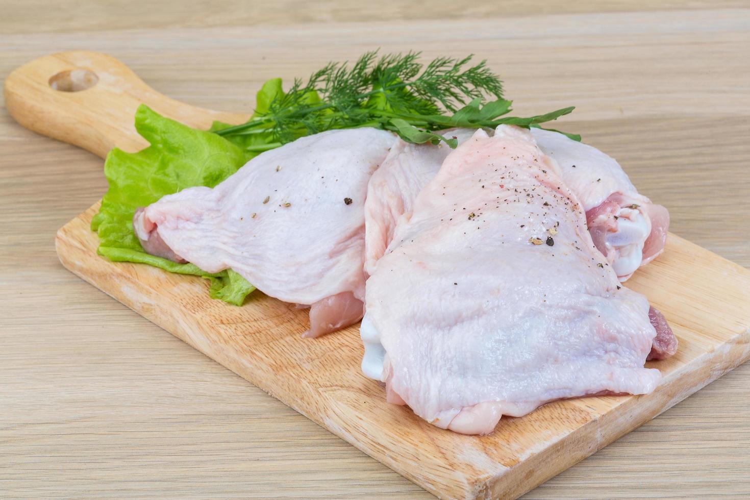 crudo pollo cosce su di legno tavola e di legno sfondo foto