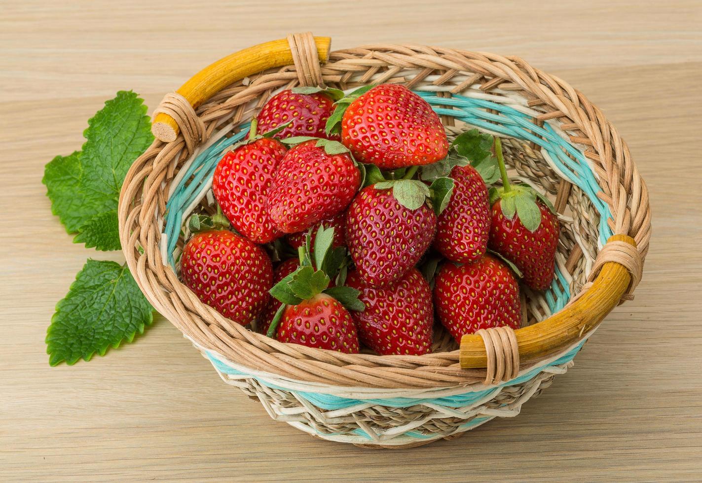 fresco fragola nel un' cestino su di legno sfondo foto