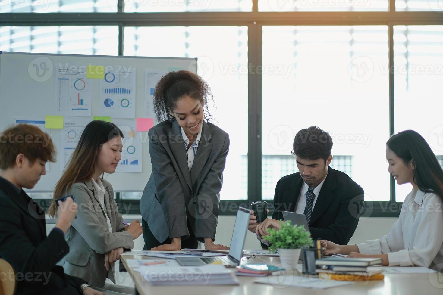 asiatico attività commerciale donna capo nel un' incontro con sua multietnico colleghi a il ufficio presentazione i saldi dati o previsione per un' progetto foto