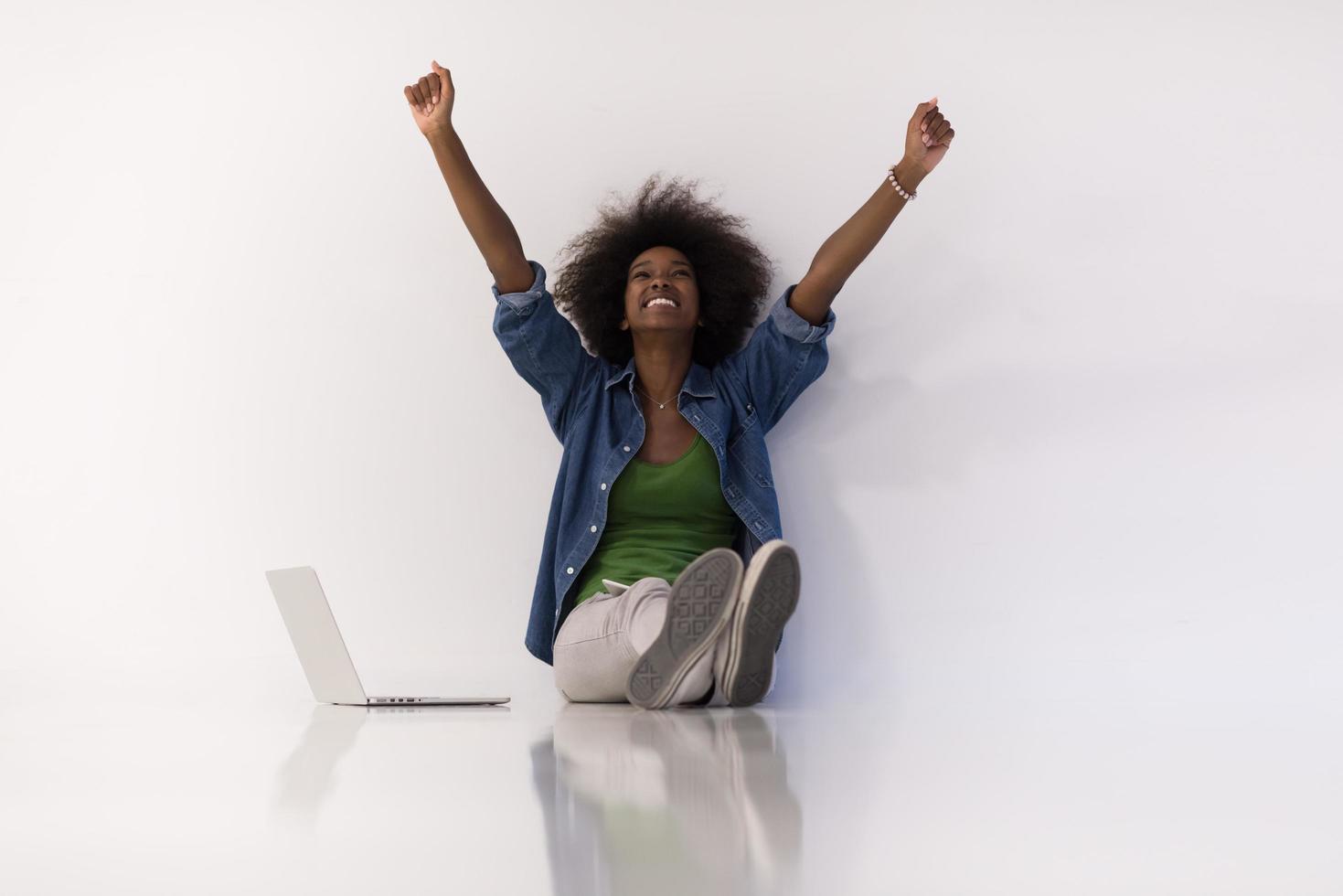 africano americano donna seduta su pavimento con il computer portatile foto