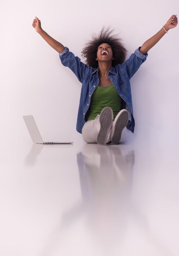 africano americano donna seduta su pavimento con il computer portatile foto