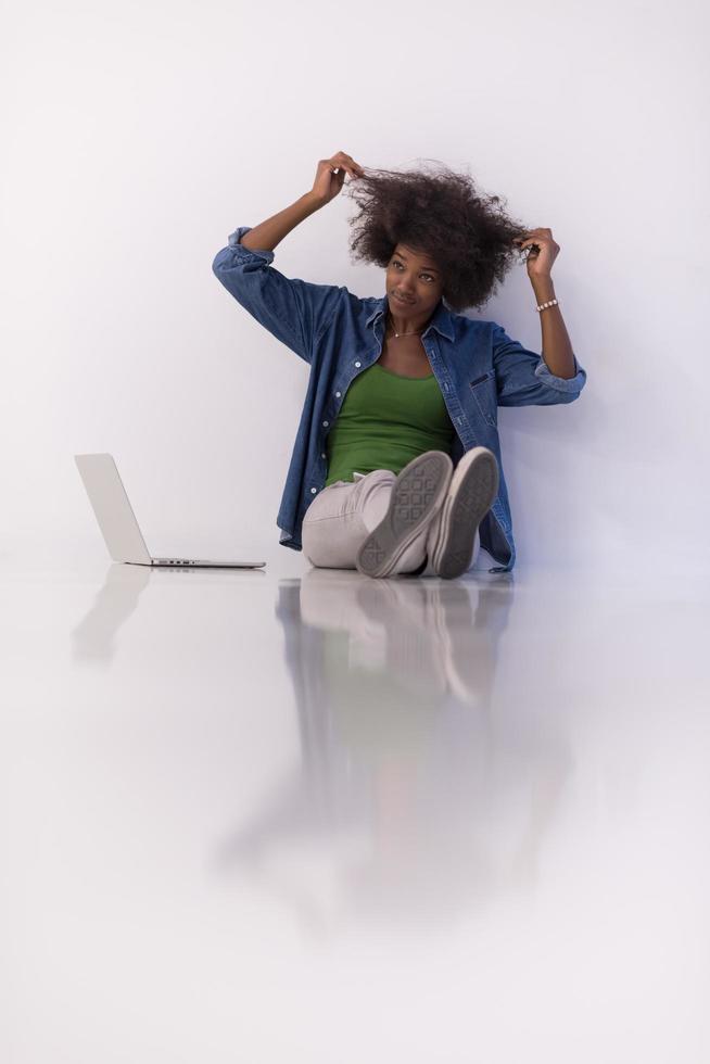 africano americano donna seduta su pavimento con il computer portatile foto