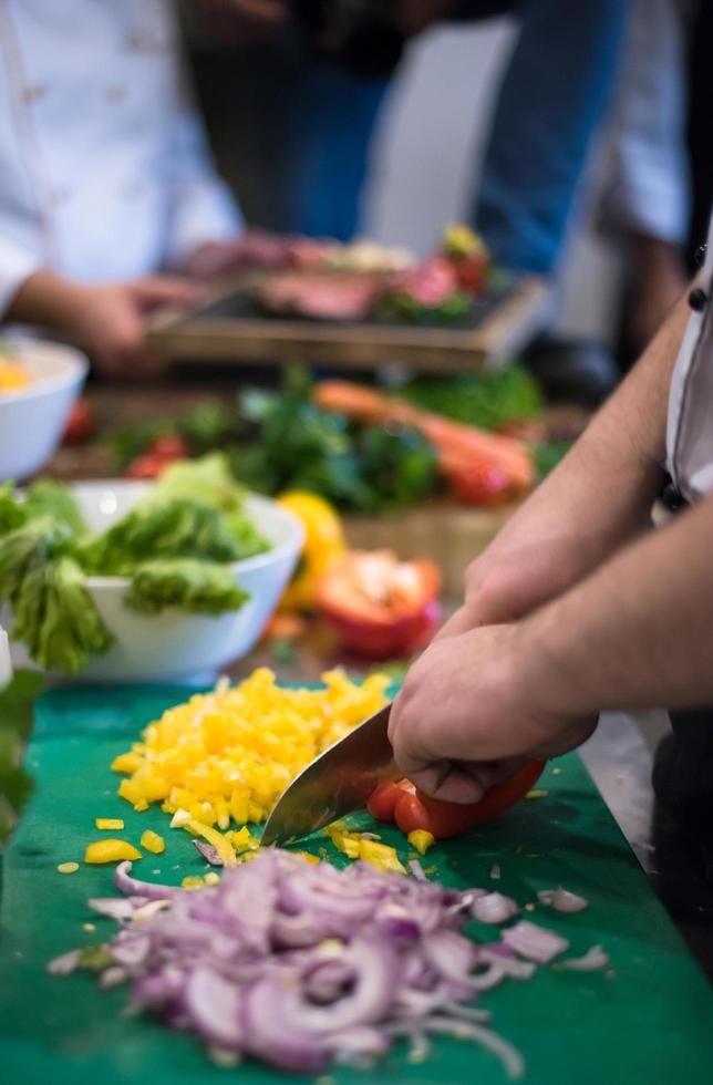 mani dello chef che tagliano verdure fresche e deliziose foto