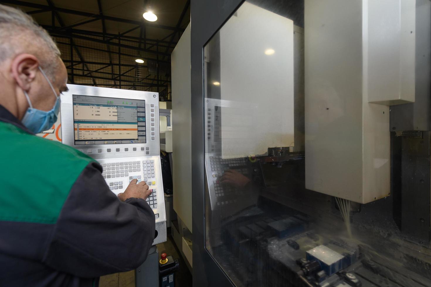 un' inteligente fabbrica lavoratore o ingegnere indossa un' viso maschera perché di un' pandemia e fa macchine nel un' produzione officina. il concetto di industria e ingegneria. foto