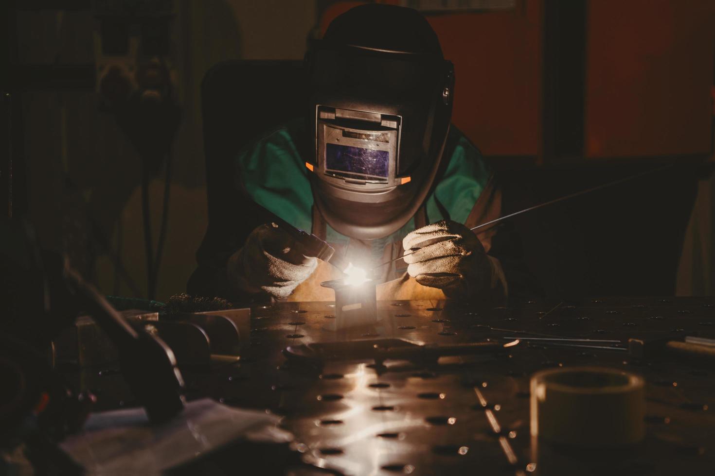 professionale saldatore esegue opera con metallo parti nel fabbrica, scintille e elettricità. industria lavoratore striscione. foto