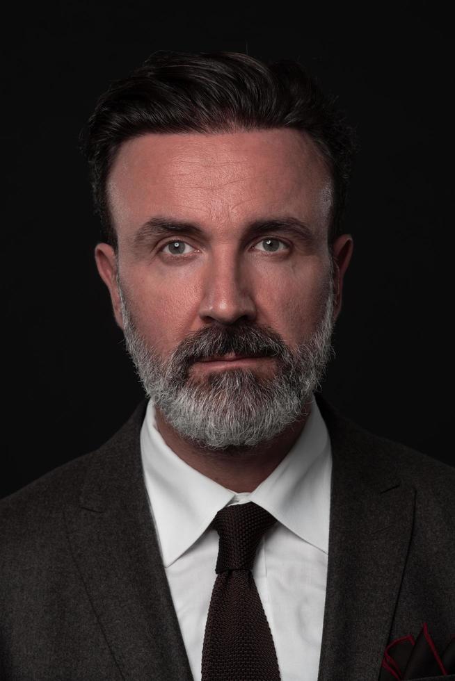 ritratto di un' elegante elegante anziano uomo d'affari con un' barba e casuale attività commerciale Abiti nel foto studio isolato su buio sfondo Esprimere a gesti con mani