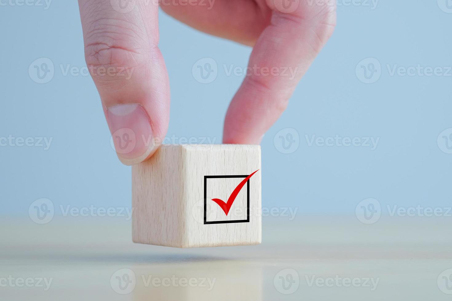 elezioni e voto, votazione, per fare elenco, lista di controllo, compito elenco, sondaggio e valutazione concetto. mano Tenere dai un'occhiata marchio su di legno bloccare. foto