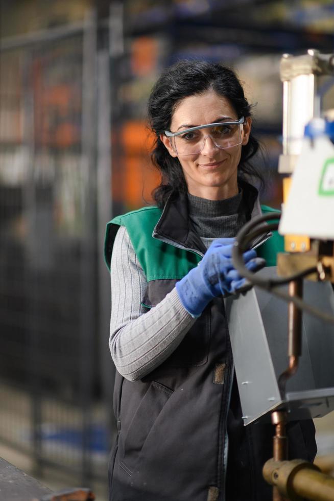 donna lavoratore indossare sicurezza occhiali controllo tornio macchina per trapano componenti. metallo tornio industriale produzione fabbrica foto