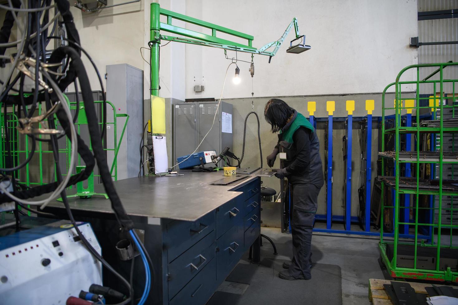 un' donna Lavorando nel il moderno metallo produzione e in lavorazione industria saldatura il Prodotto e prepara esso per un' cnc macchina foto