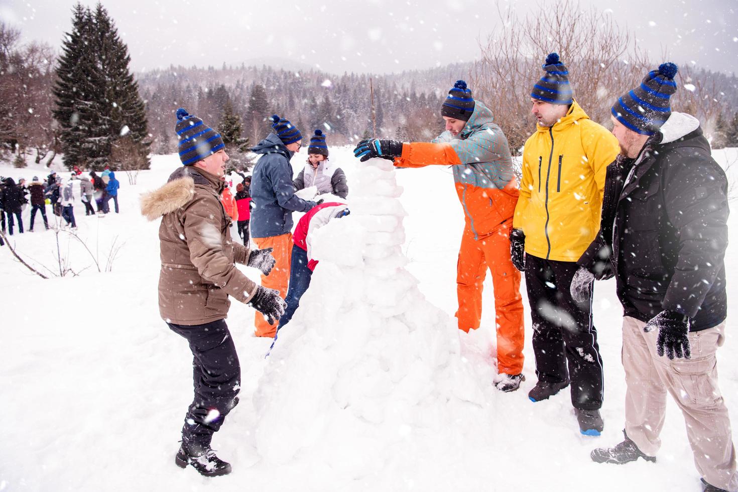 gruppo di giovane persone fabbricazione un' pupazzo di neve foto