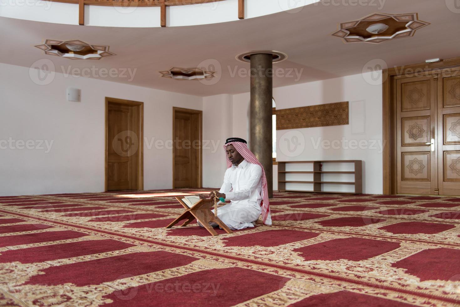 uomo d'affari nero in Dishdasha sta leggendo il Corano foto
