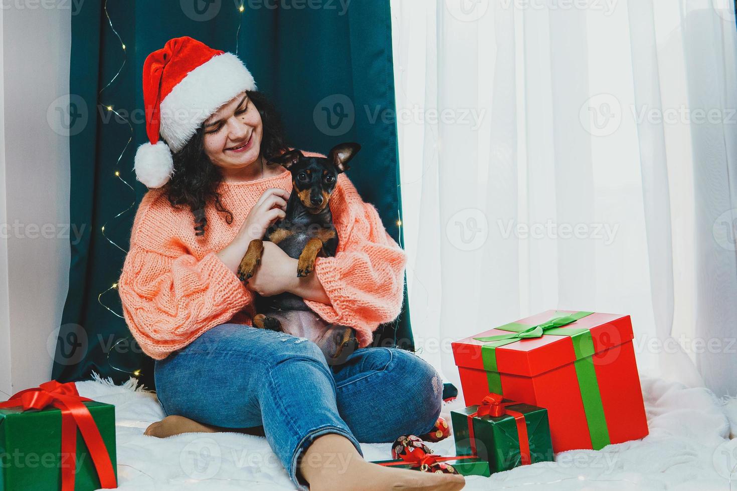 ritratto di giovane donna giocando con divertente cane miniatura pinscher in giro Natale palla e regalo scatole foto