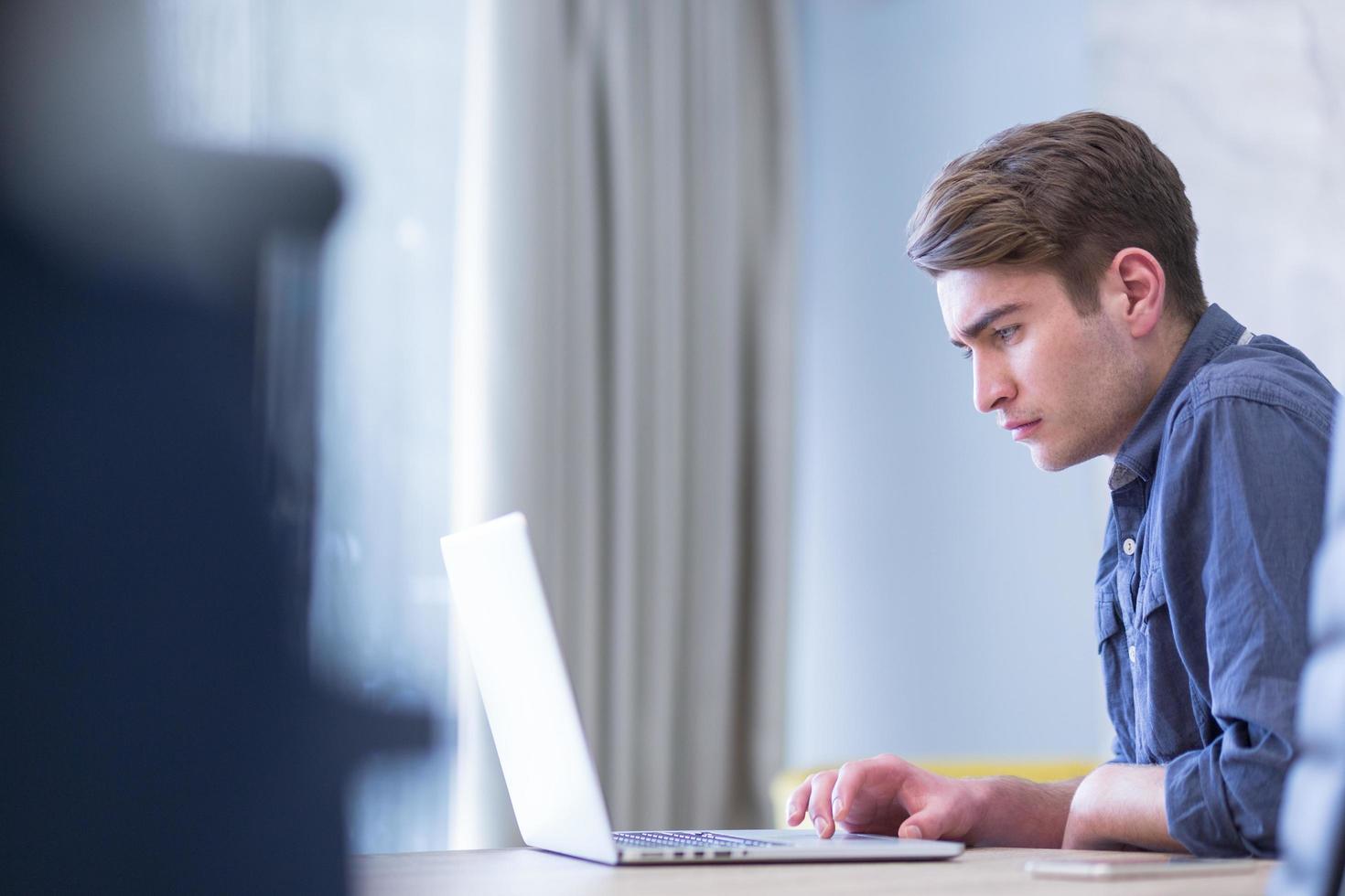 uomo d'affari che lavora utilizzando un laptop nell'ufficio di avvio foto