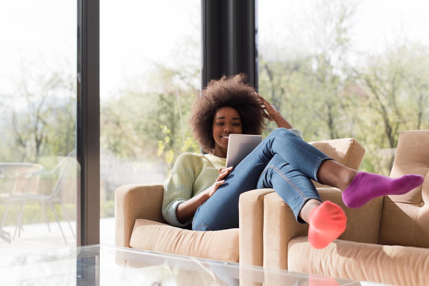 giovane africano americano donna a casa utilizzando digitale tavoletta foto