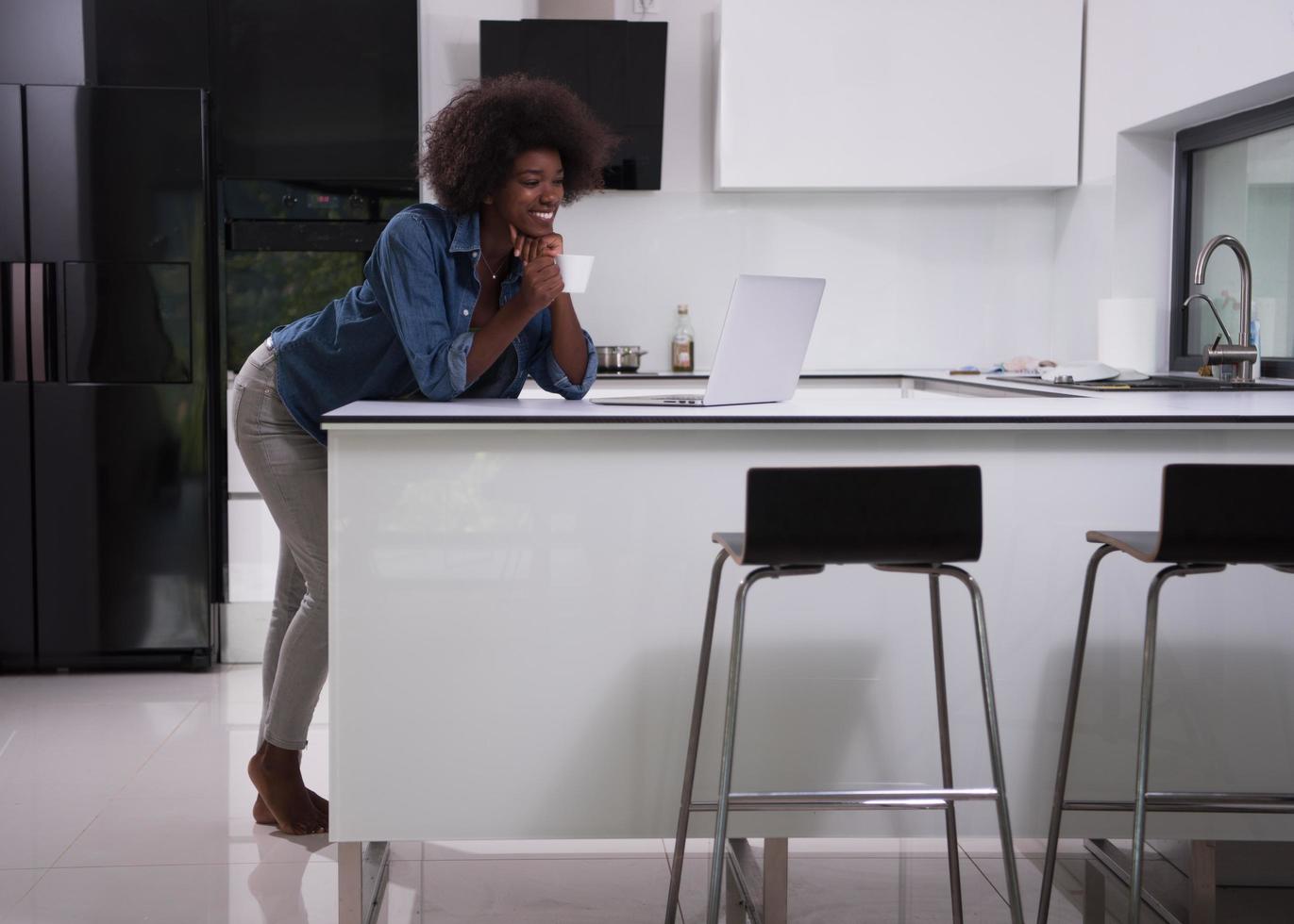 sorridente nero donna nel moderno cucina foto