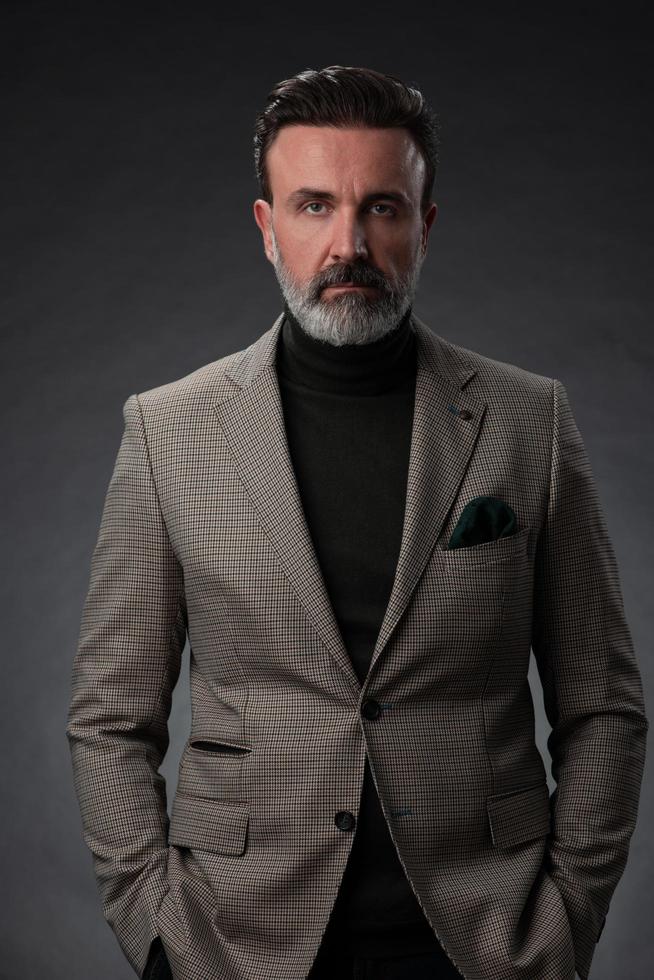 ritratto di un' elegante elegante anziano uomo d'affari con un' barba e casuale attività commerciale Abiti nel foto studio isolato su buio sfondo Esprimere a gesti con mani