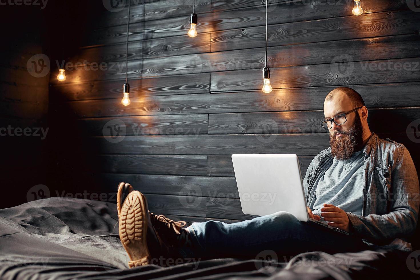 stile di vita riuscito libero professionista uomo con barba ottiene nuovo obbiettivo con il computer portatile nel soffitta interno. foto